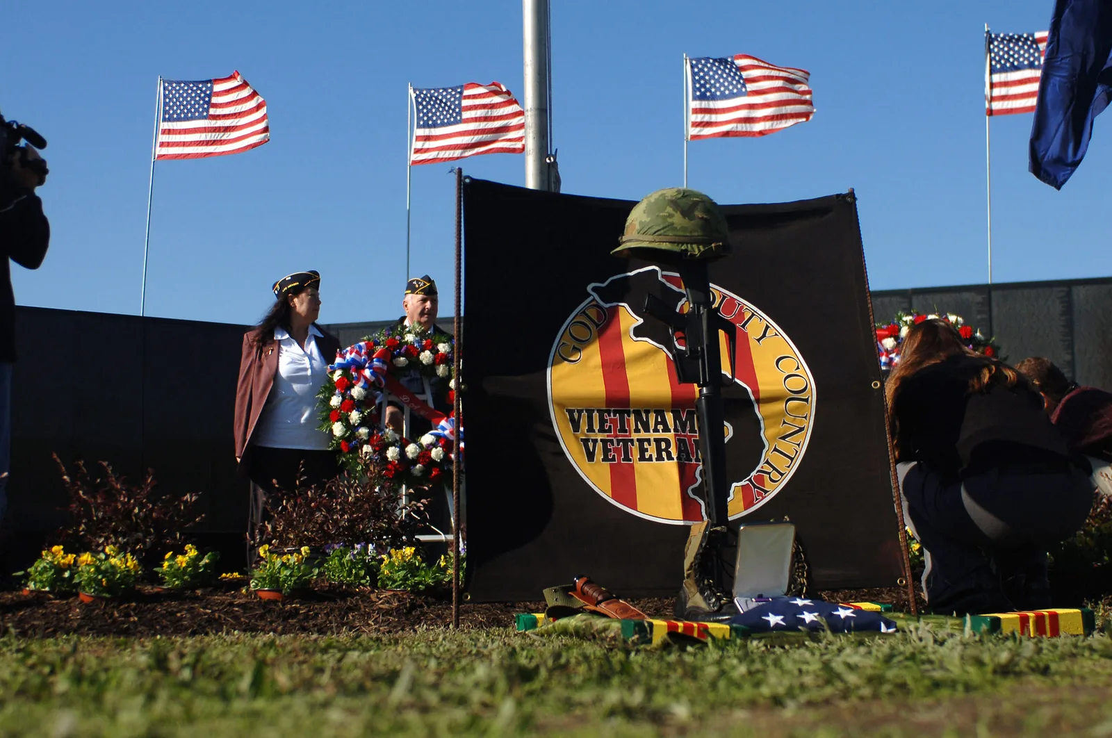 Wreaths, flags and a battlefield cross laid for Vietnam veterans at a memorial ceremony at Mount Trashmore Park in Virginia Beach.