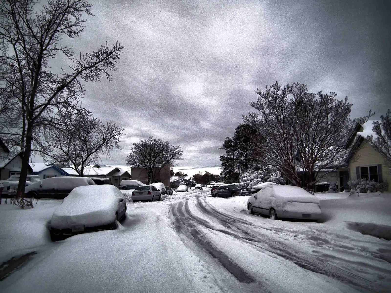 Houses and parked cars along a residential street in Virginia Beach after a snowfall.
