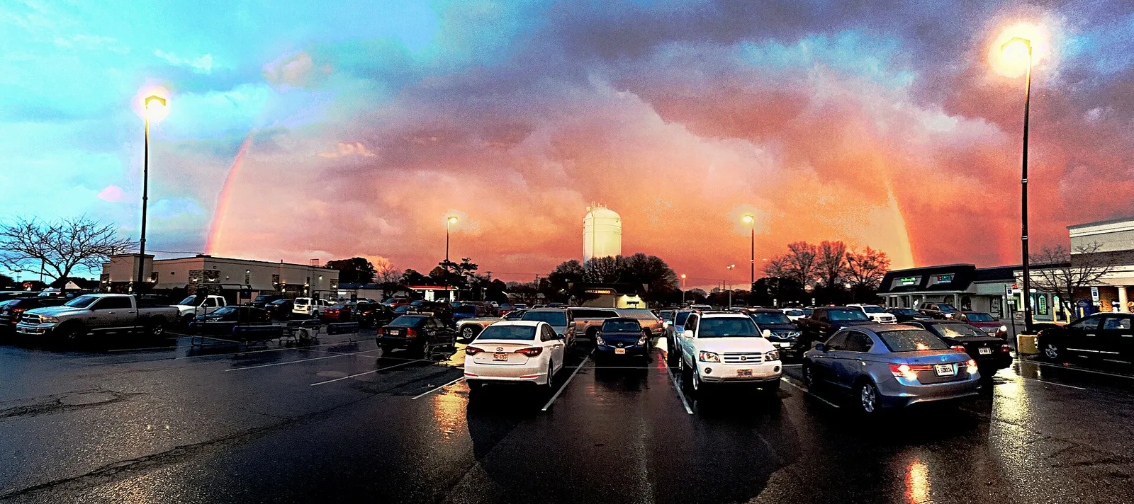 A rainbow over a shopping center parking lot and a water tower in Virginia Beach.