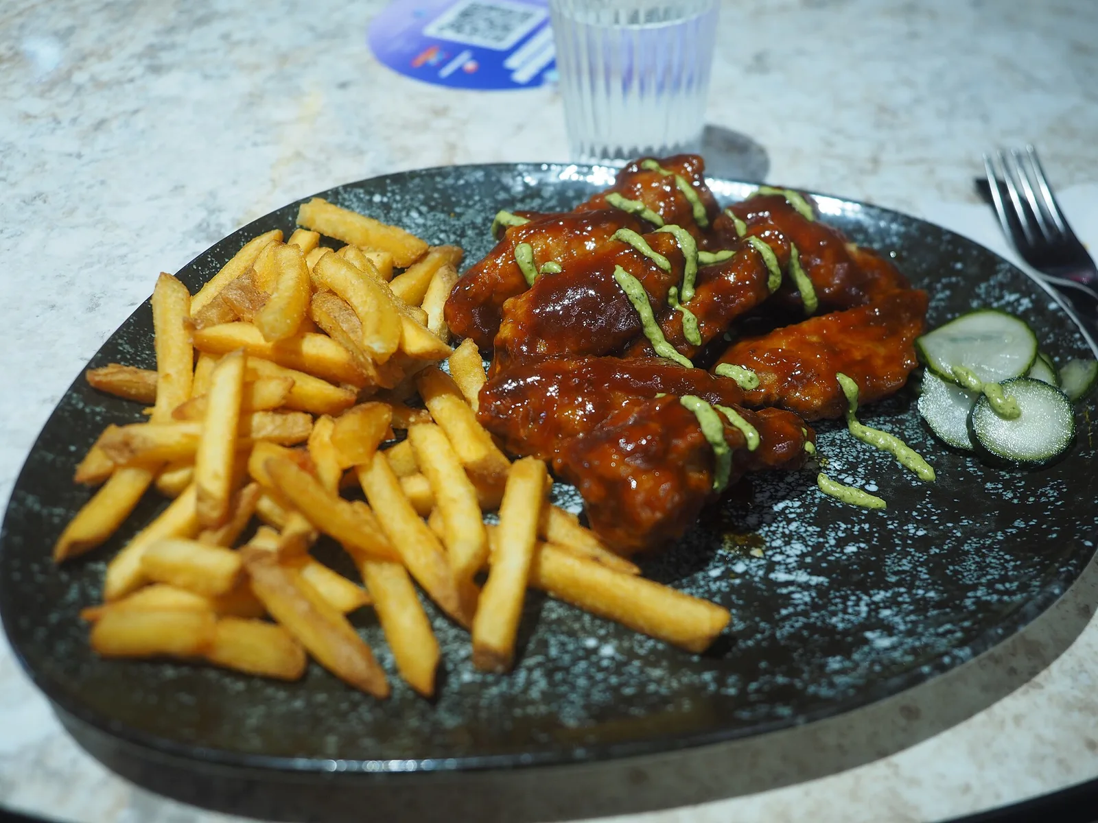 Sauced chicken wings with fries at a restaurant in Helsinki, Finland.